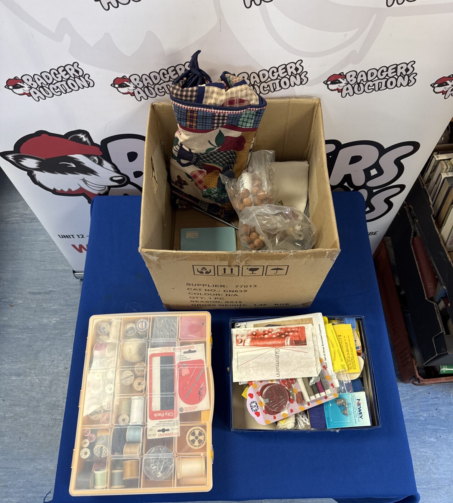 Open box of sewing and embroidery supplies, thread and needles.
