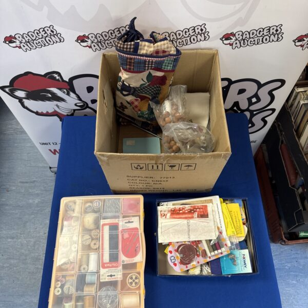 Open box of sewing and embroidery supplies, thread and needles.