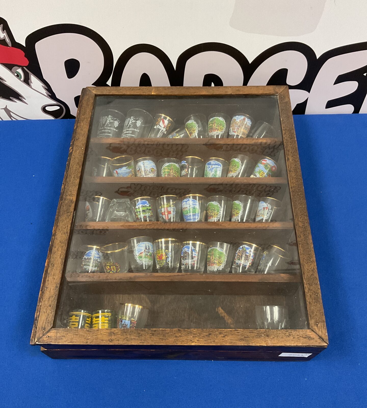 Wooden shot glass display case with miniature glass collection.