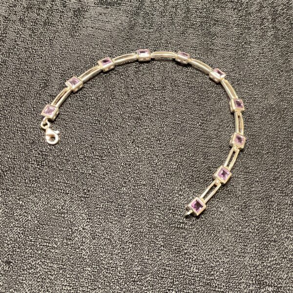 Close-up of a silver amethyst bracelet with purple gemstones.