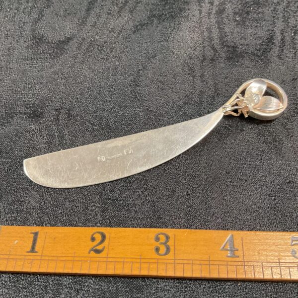 Antique silver butter knife with ornate handle, full view.