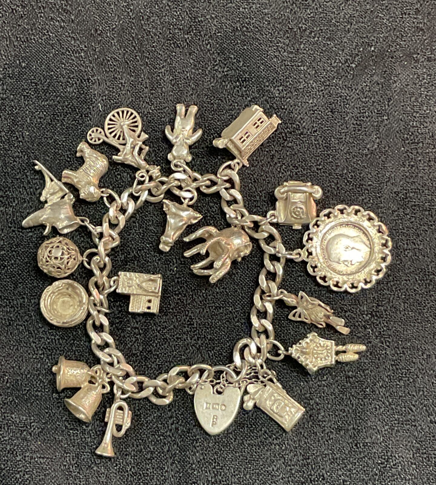 Vintage silver charm bracelet with seventeen detailed charms.
