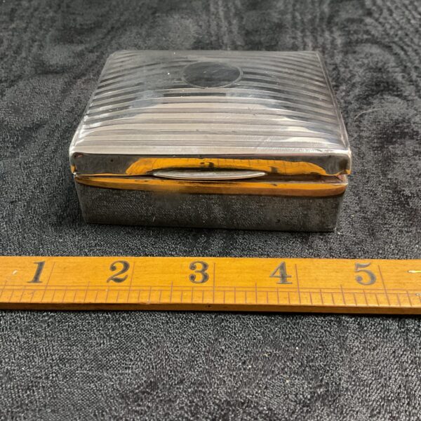 Vintage silver cigarette box with engine-turned design.
