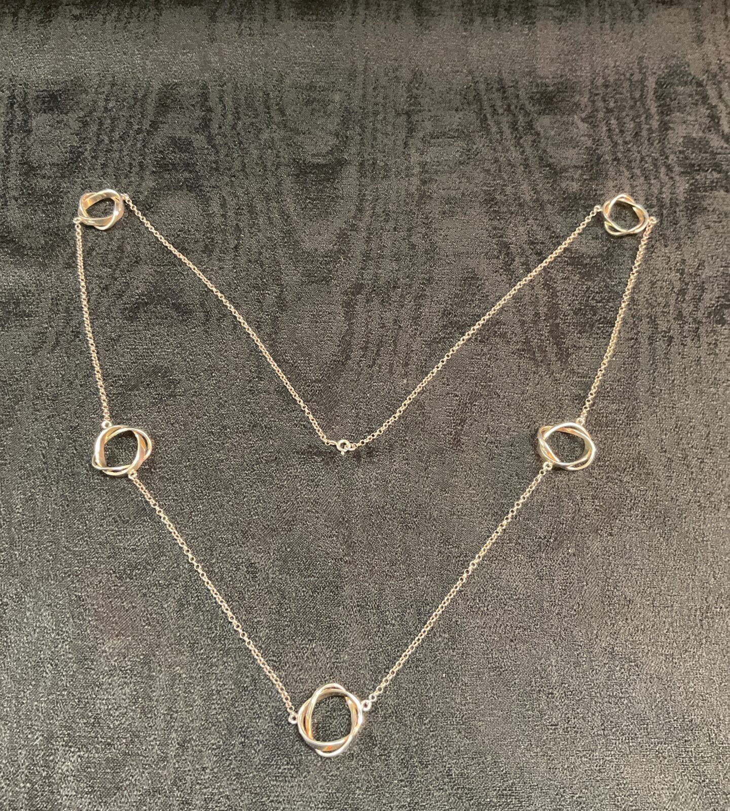 Silver circle necklace on dark background, minimalist jewellery.