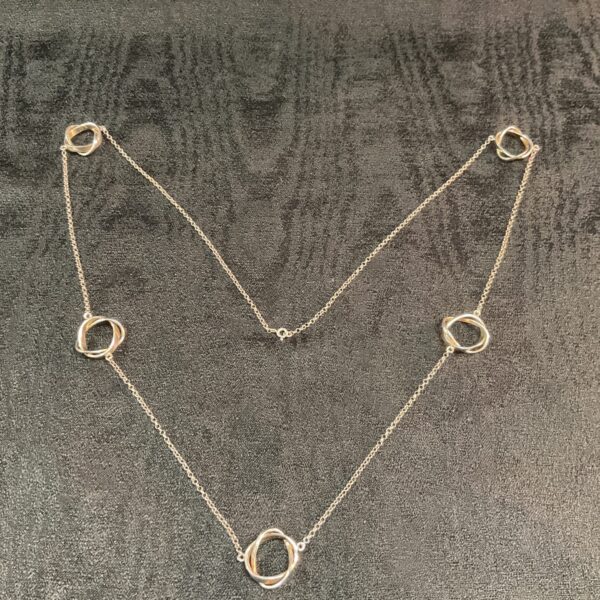 Silver circle necklace on dark background, minimalist jewellery.