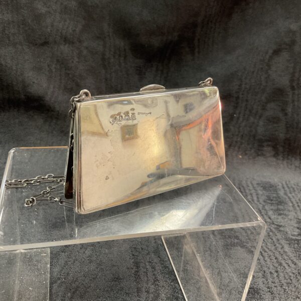 Vintage silver evening purse with chain, displayed on a clear stand.