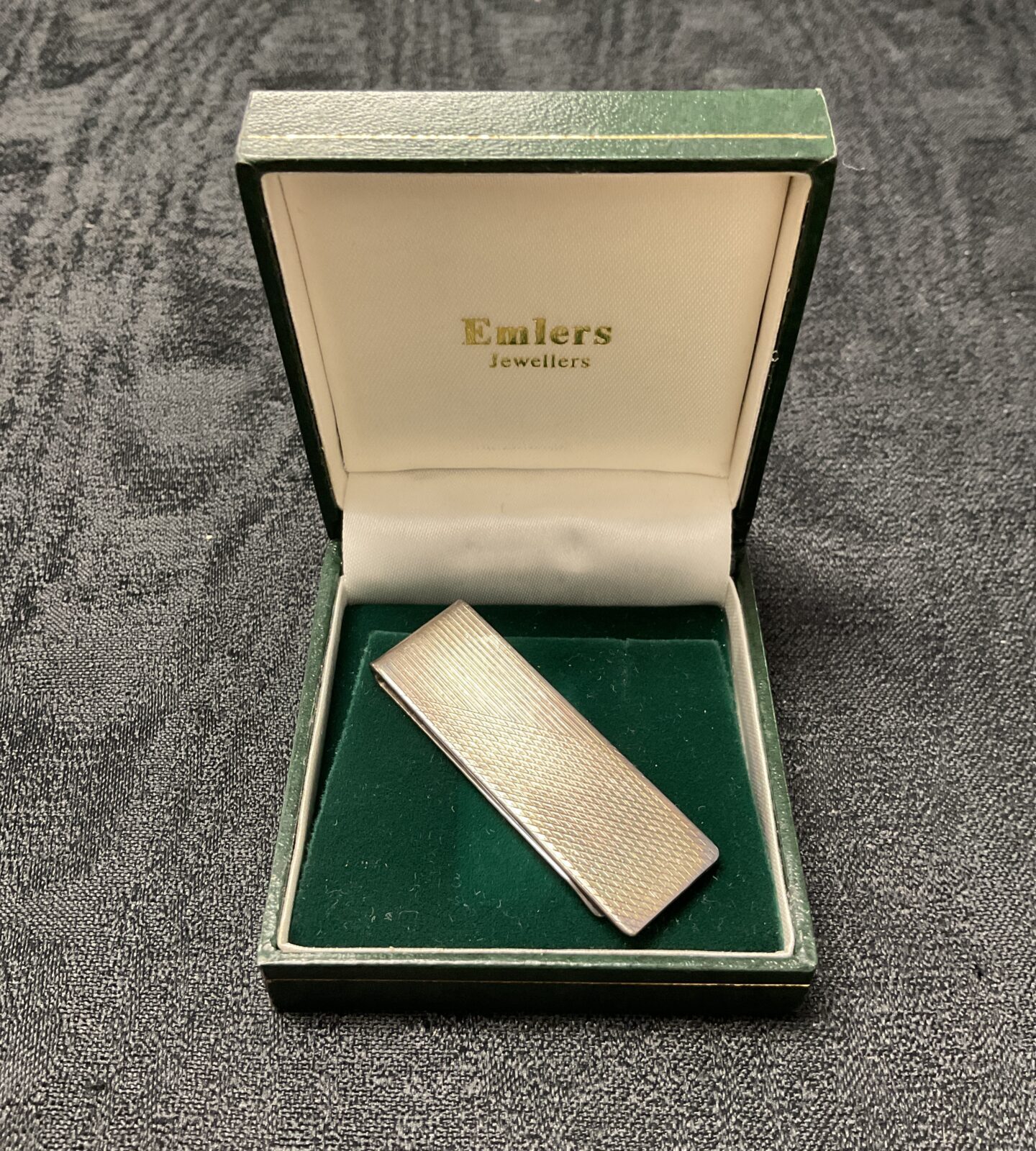 Hallmarked silver money clip on display, vintage collectible.