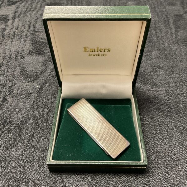 Hallmarked silver money clip on display, vintage collectible.
