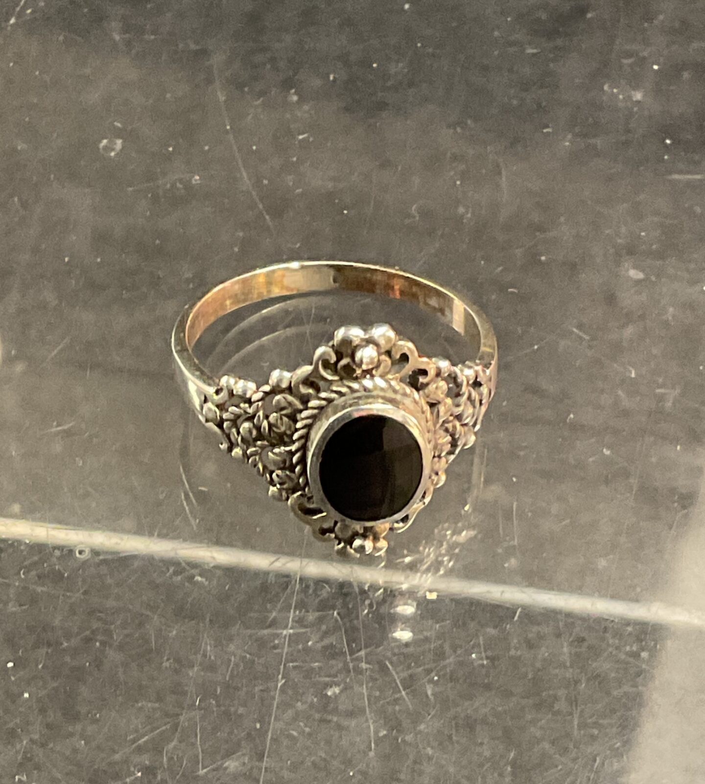 Detailed silver ring with black onyx gemstone.
