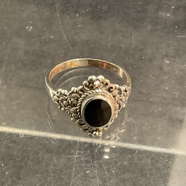 Detailed silver ring with black onyx gemstone.