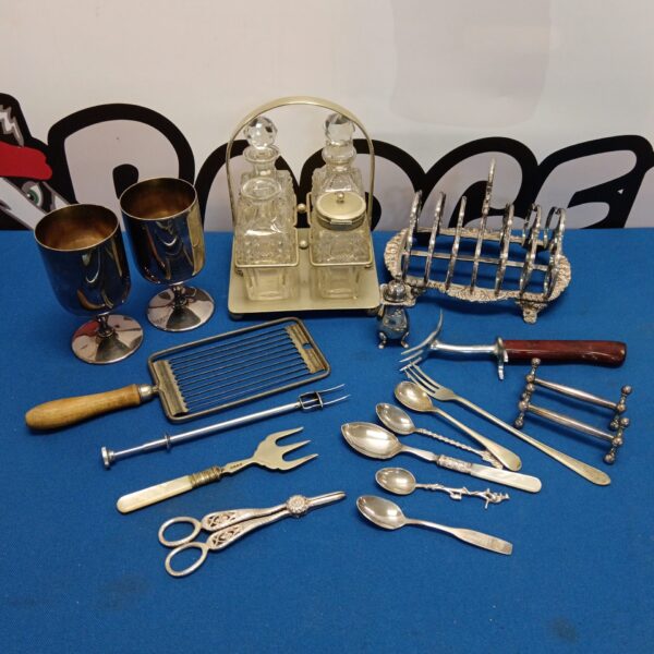 Vintage silver plate cruet set and toast rack on a blue surface.