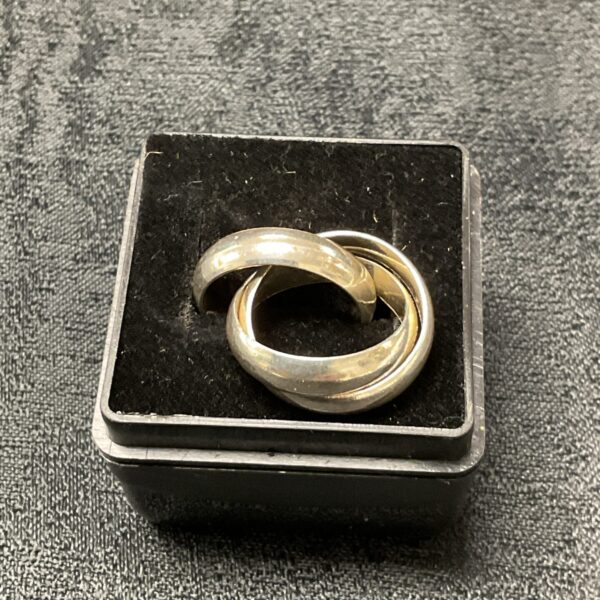 Close-up of a silver puzzle ring with interlocking bands.