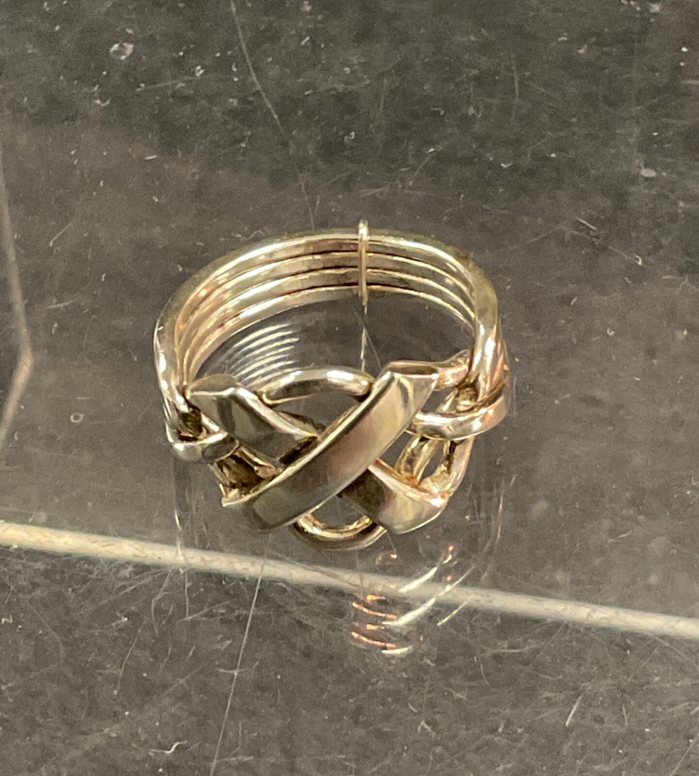 Close-up of a silver puzzle ring with interlocking bands.