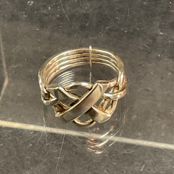 Close-up of a silver puzzle ring with interlocking bands.