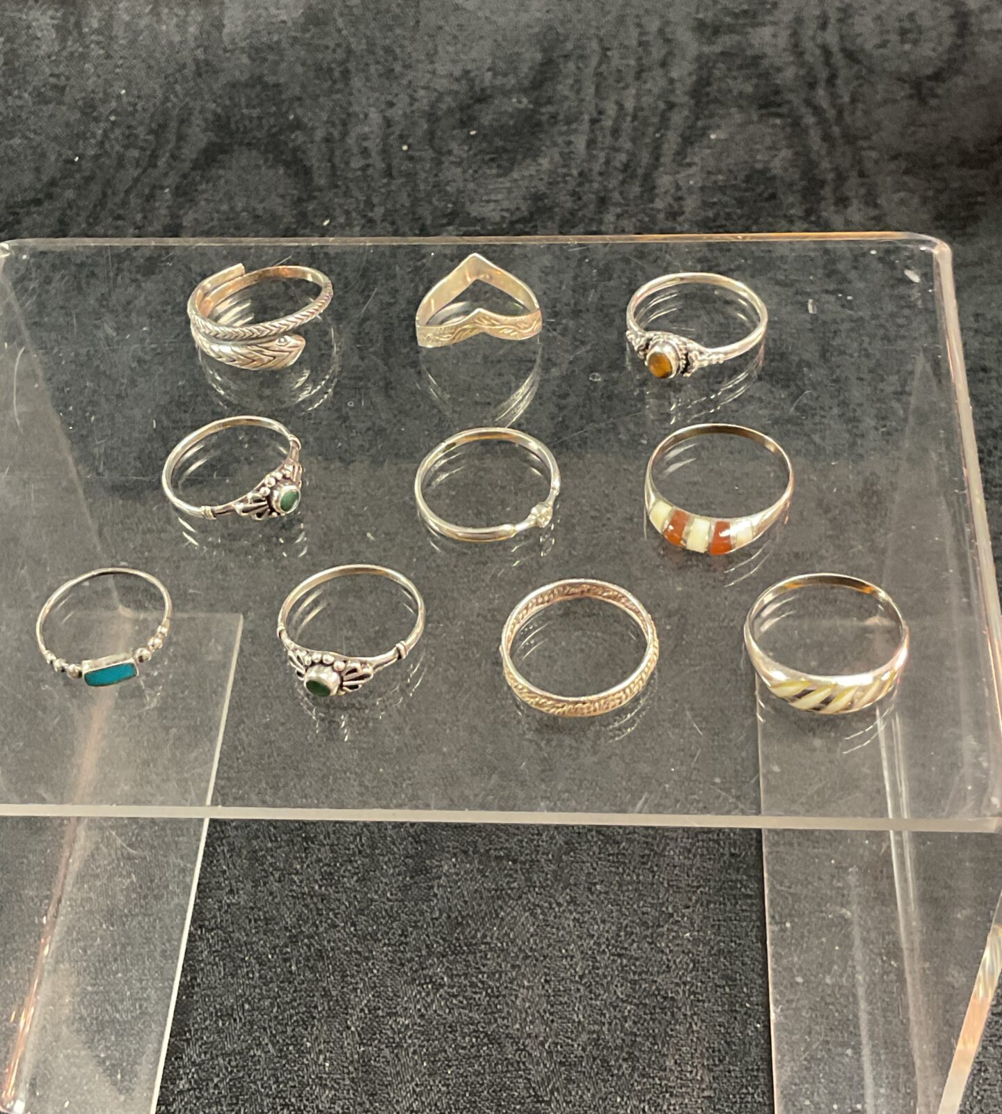 Assorted silver rings displayed on a clear stand.
