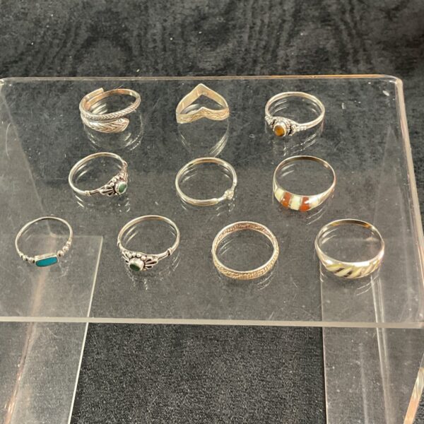Assorted silver rings displayed on a clear stand.