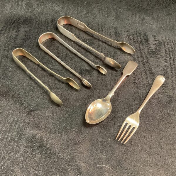 Vintage silverplate sugar tongs, spoon, and fork set displayed.