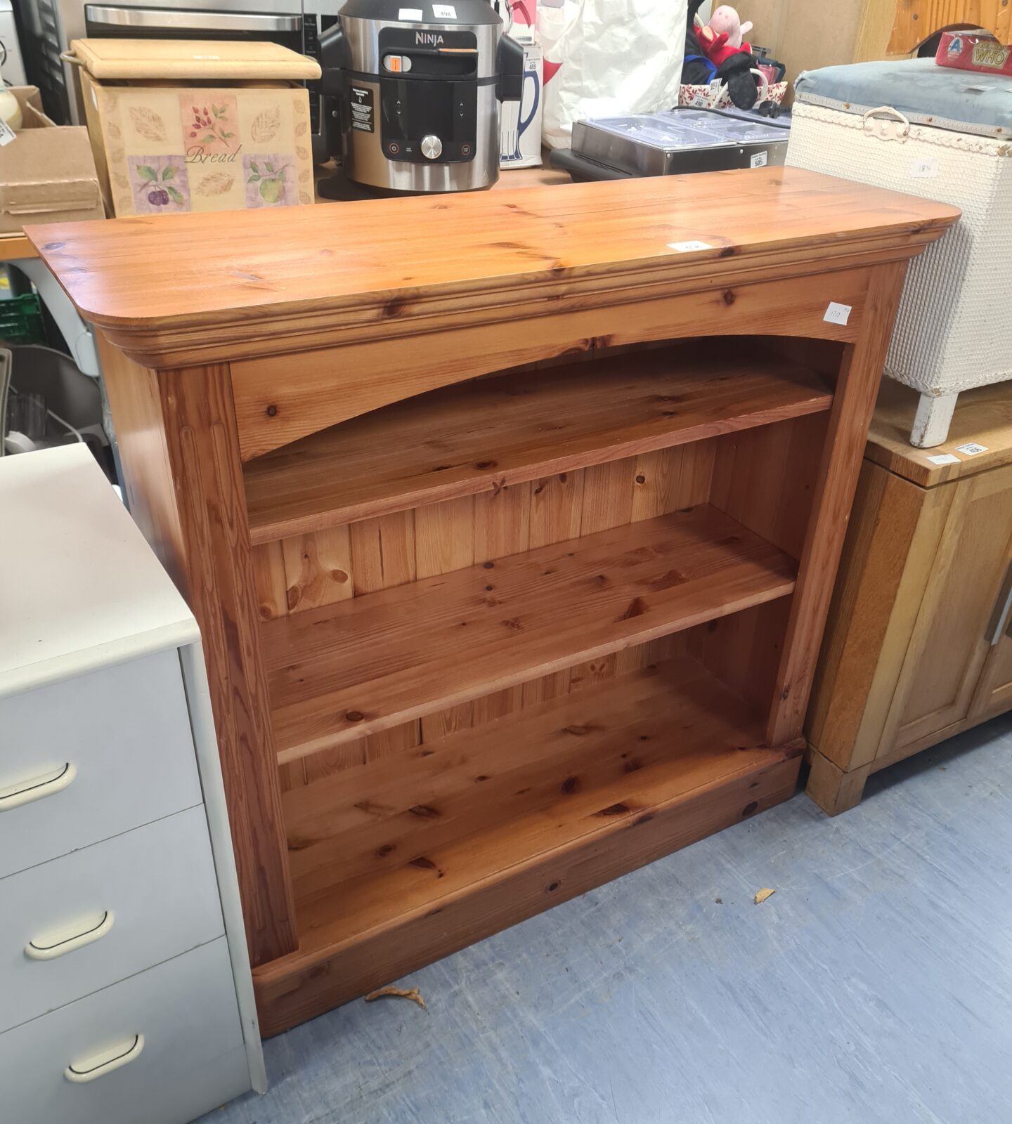 Small pine bookcase with three shelves, rustic wooden storage.