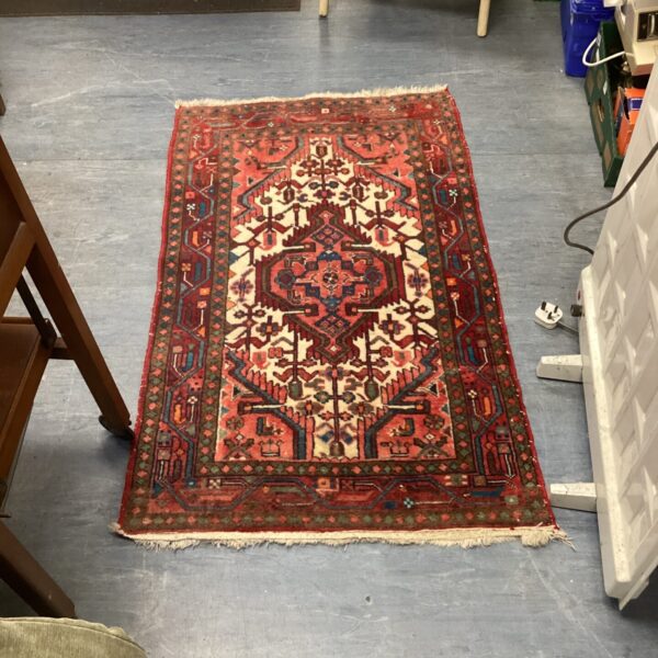 Vintage small red rug with traditional Oriental design.