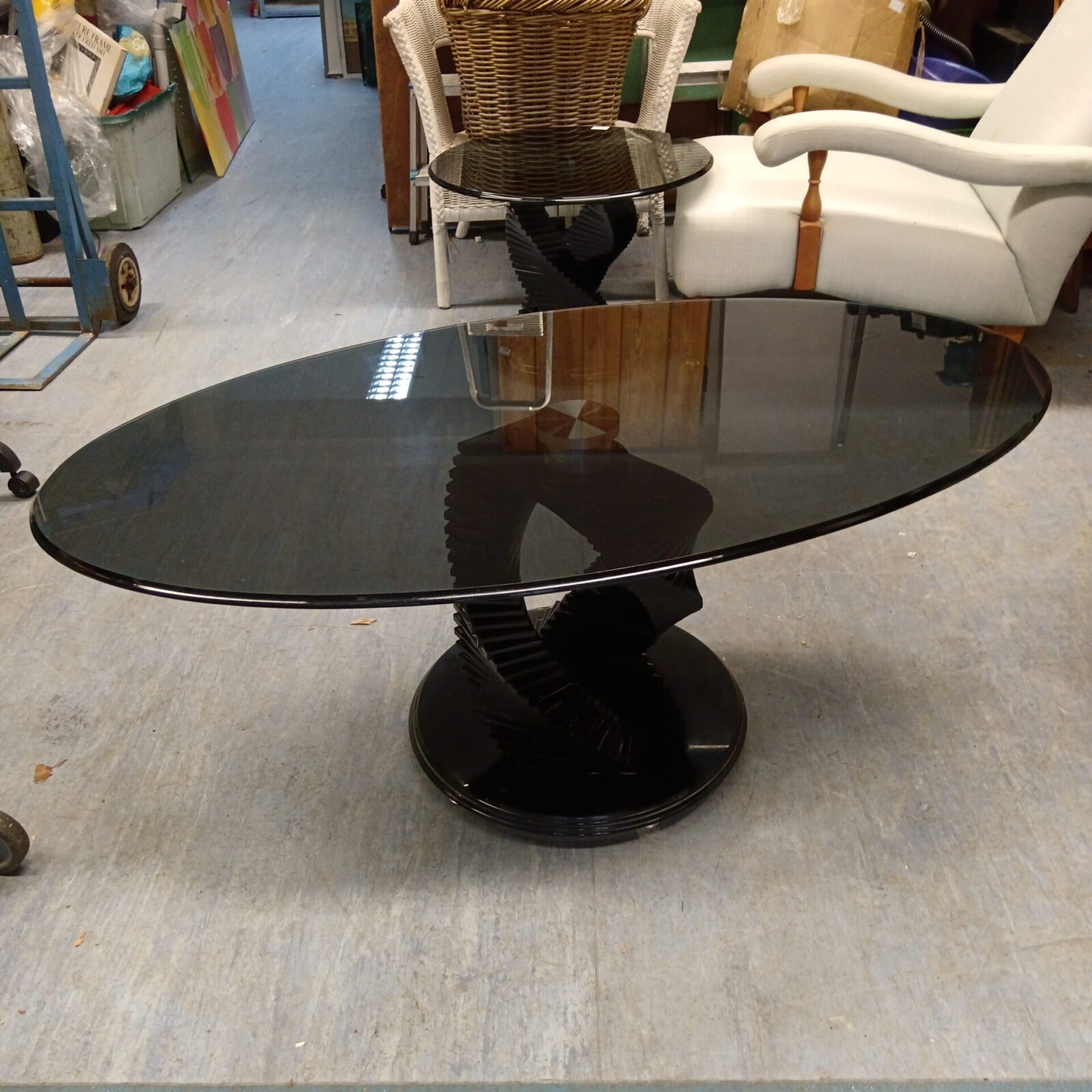 Black helix base supporting a large smoked glass coffee table.