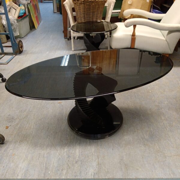 Black helix base supporting a large smoked glass coffee table.