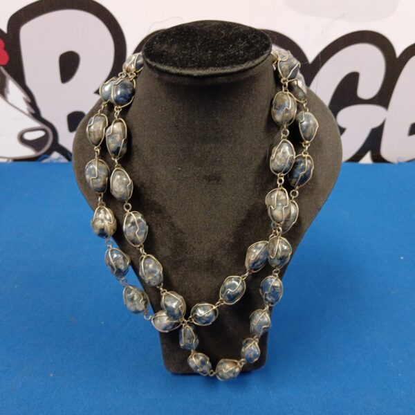 Close-up of a chunky sodalite wire wrapped necklace with blue stones.