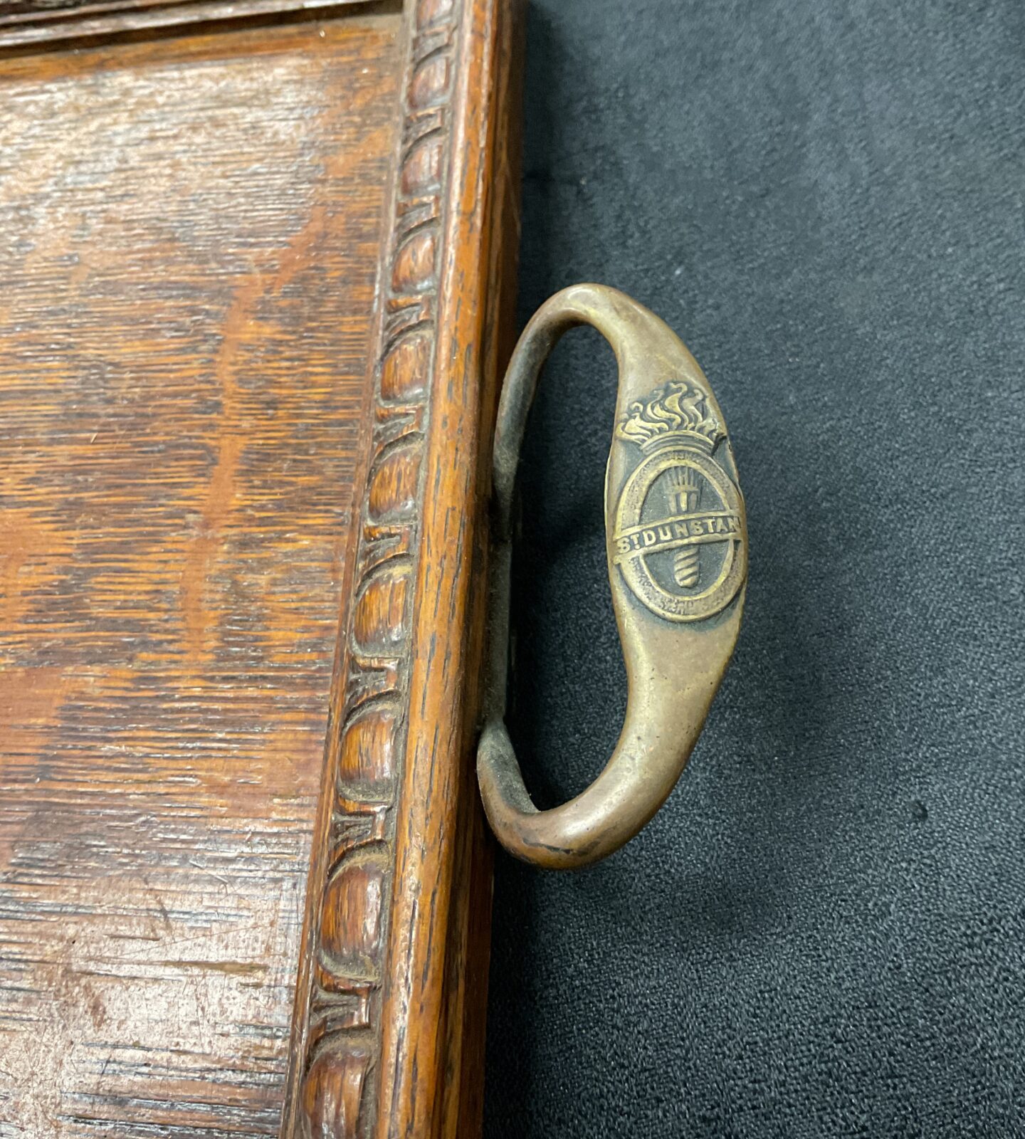 Close-up of brass handles on antique St Dunstan’s WWI oak tray.