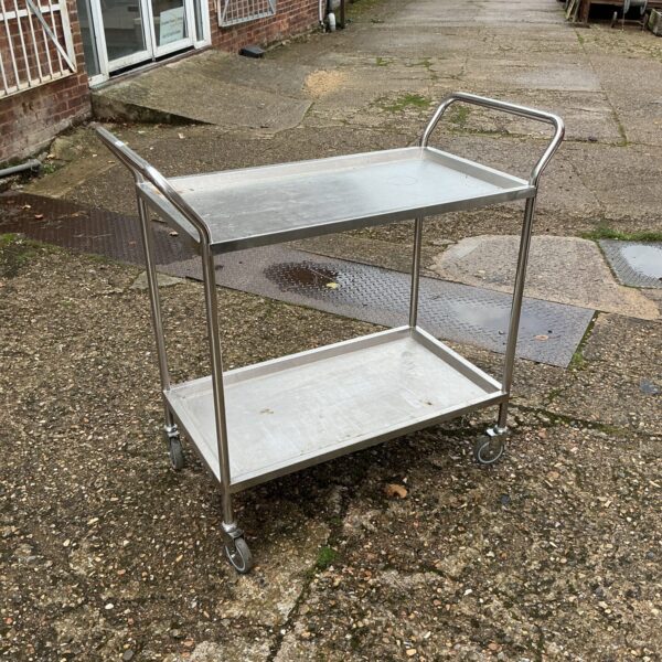 Stainless steel trolley with two tiers and castors.