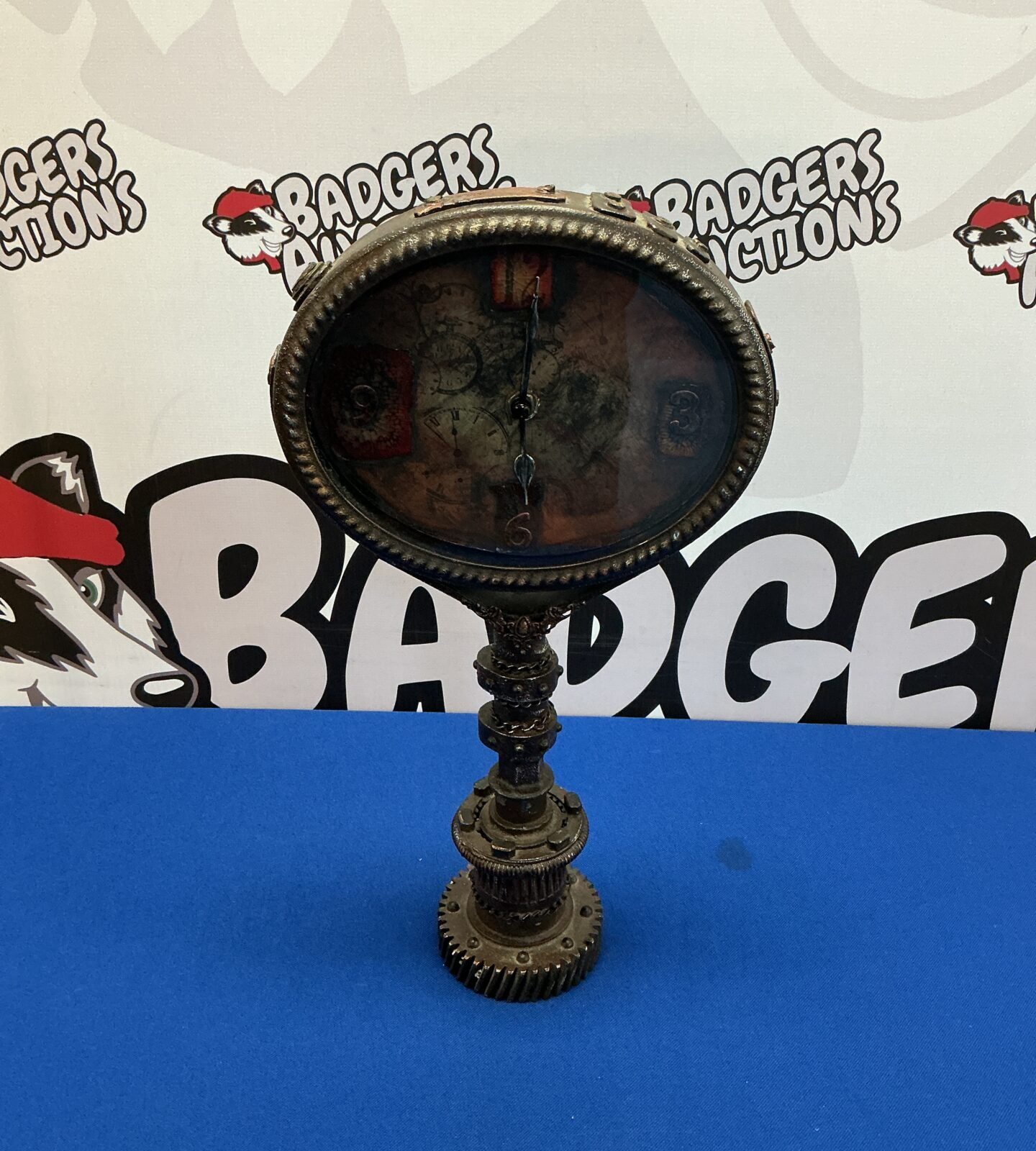 Intricate steampunk clock with a dark metal crankshaft base.