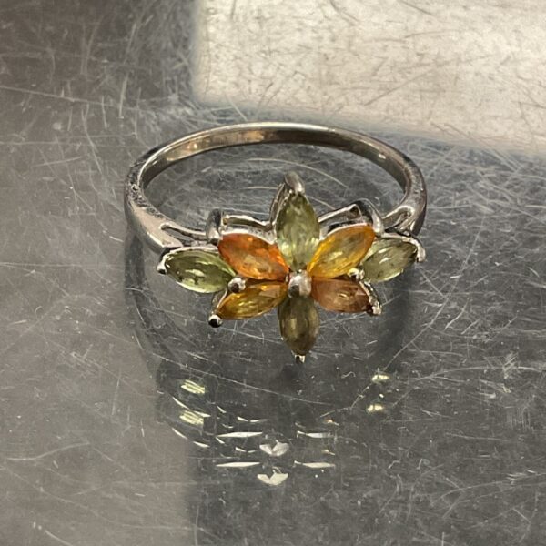 Close-up of a sterling silver ring with yellow and green stones.