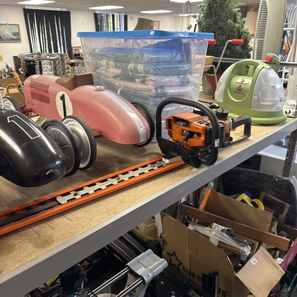 Used Stihl HS80 hedge trimmer on a shelf with other tools.