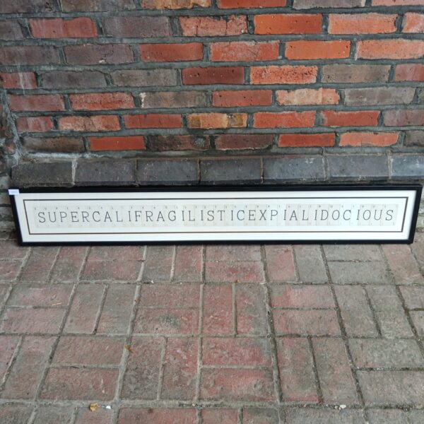 Vintage supercalifragilisticexpialidocious artwork framed against a brick wall.