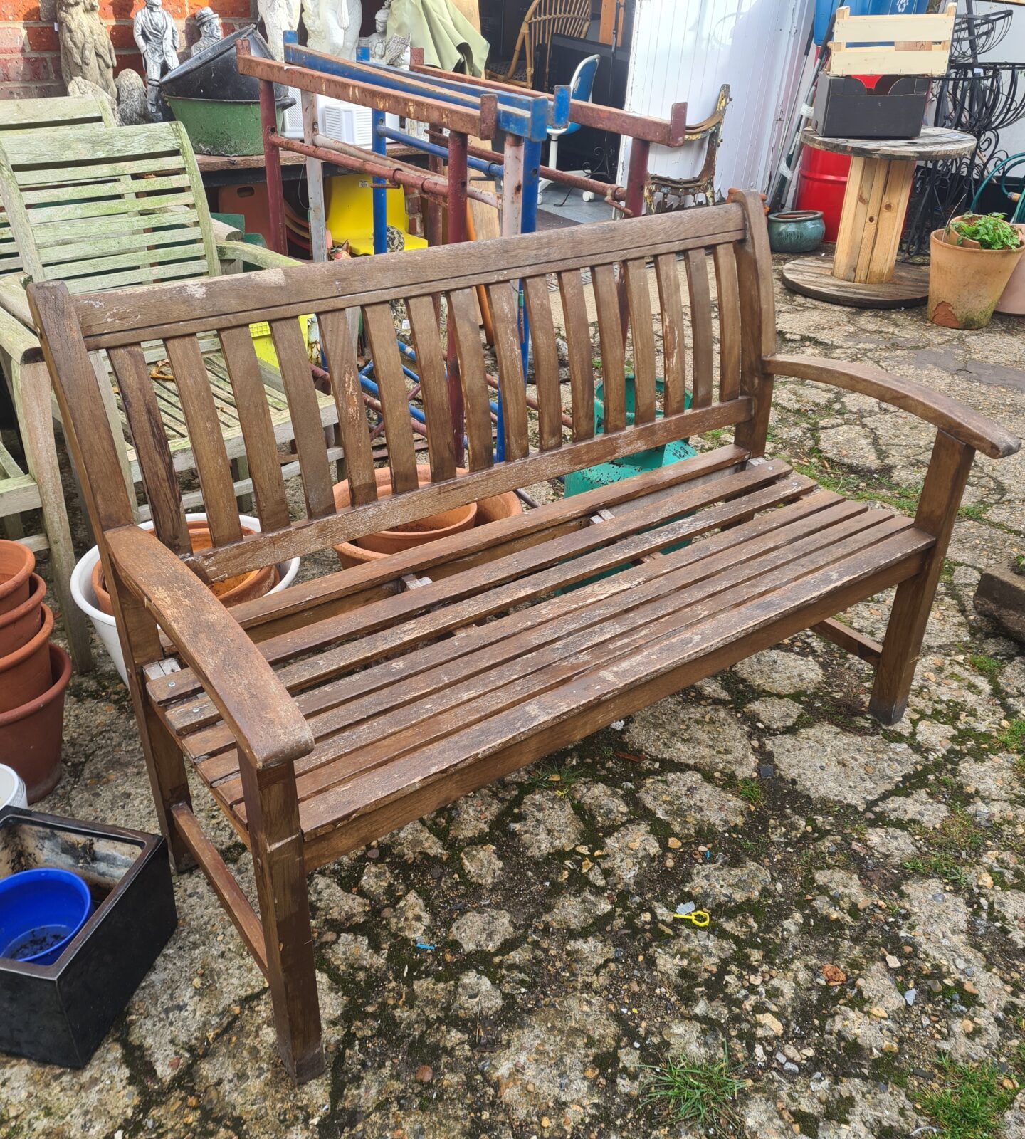 Weathered teak garden bench with slatted seat and back.