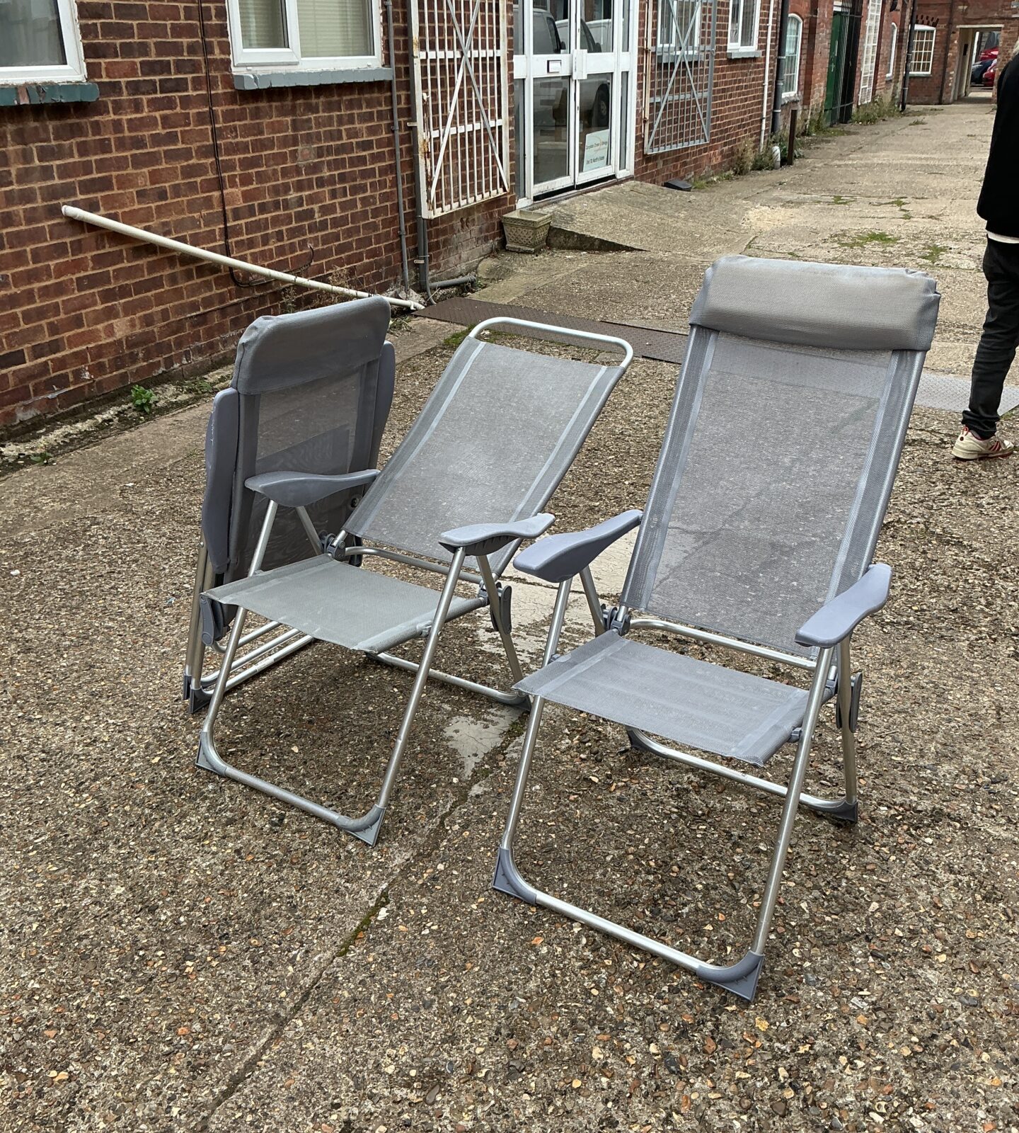 Three folding garden chairs on a paved patio.