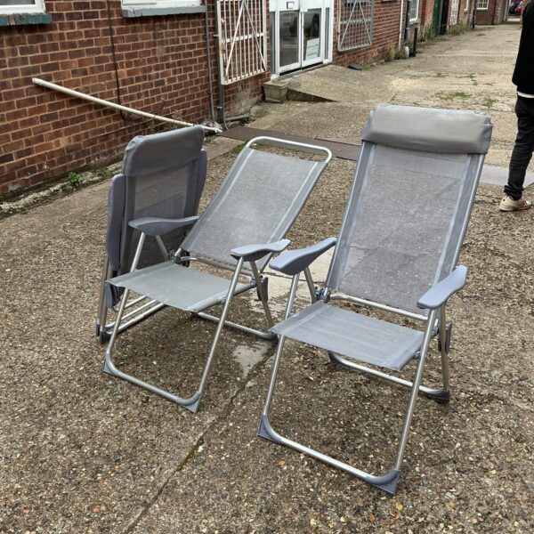 Three folding garden chairs on a paved patio.