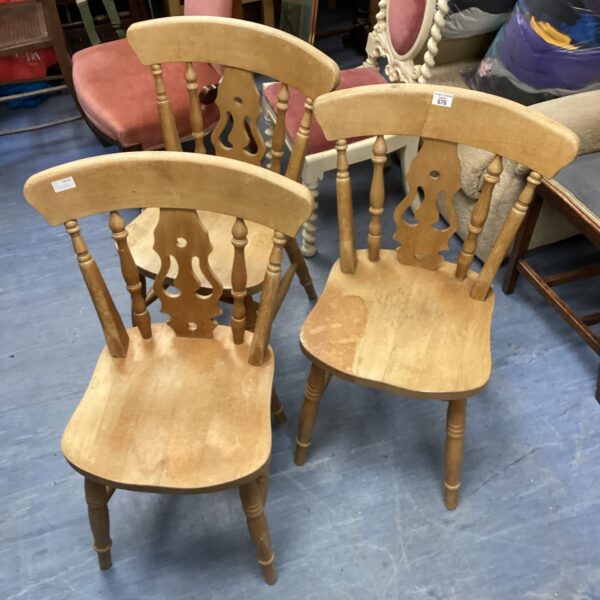 Three vintage pine farmhouse chairs with curved back splats.