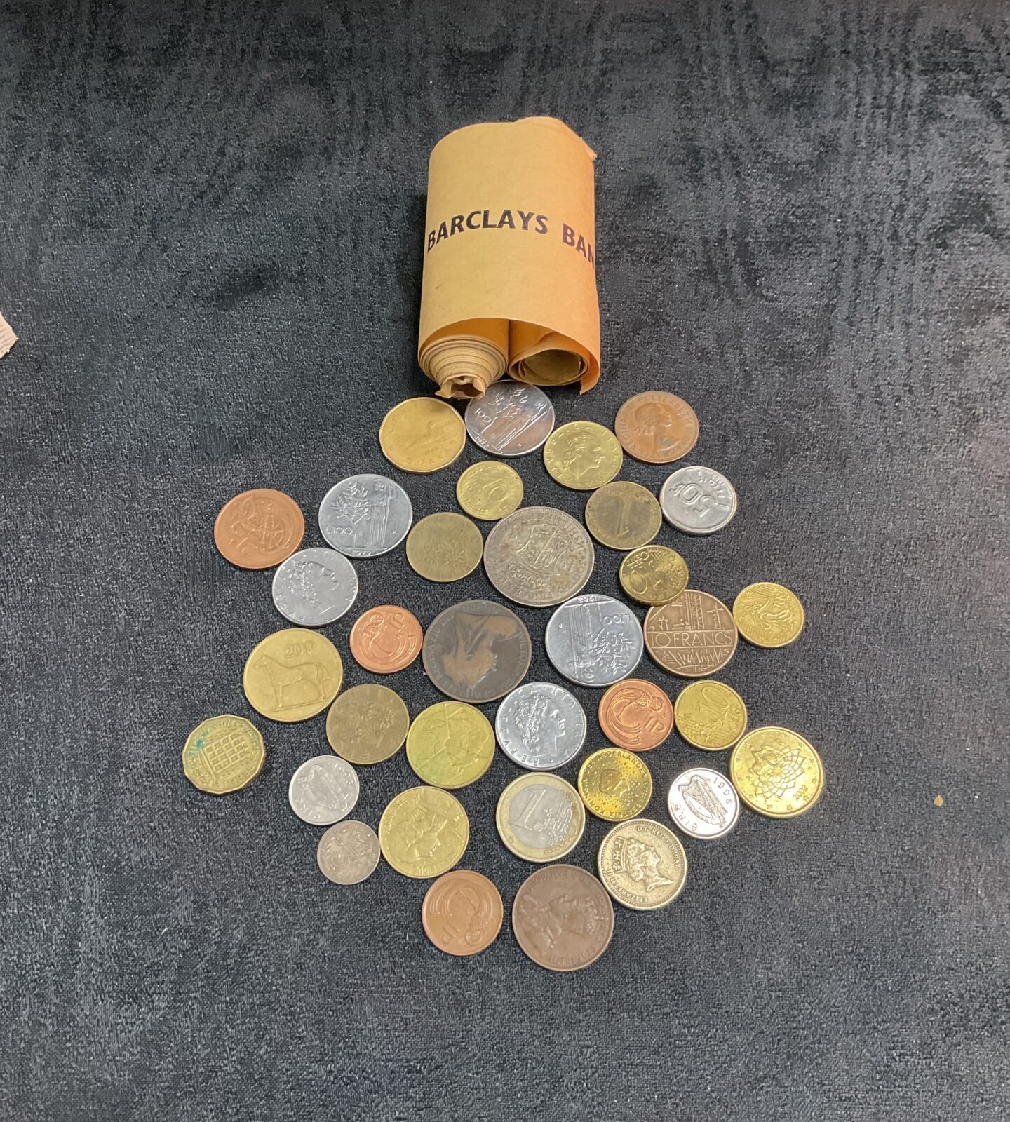 Mixed UK coins in a tub and Barclays Bank rolls.