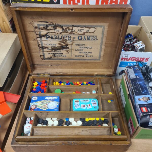 Victorian parlour games box open, showing a variety of colourful game pieces.
