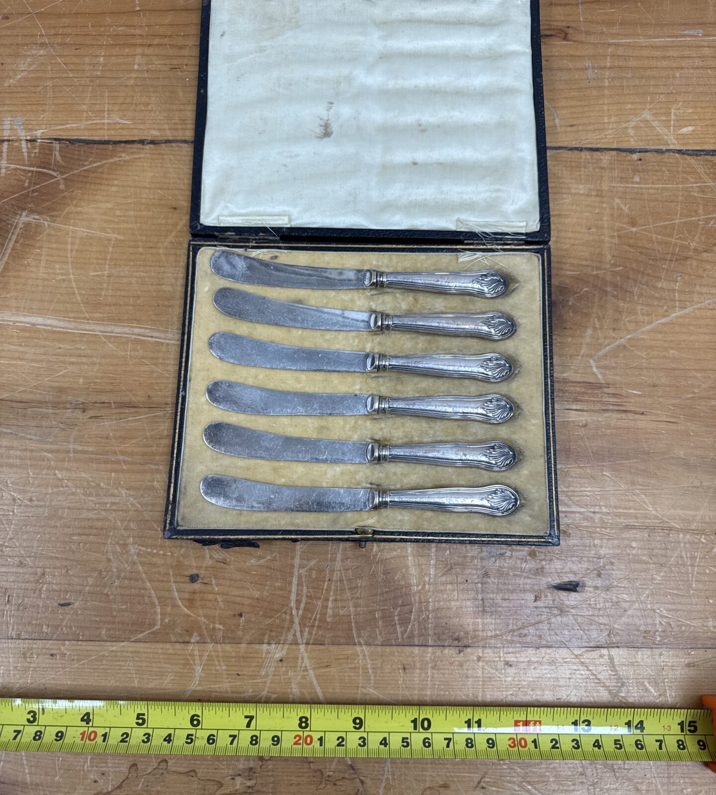 Cased set of six Victorian silver cake knives on a wooden surface.