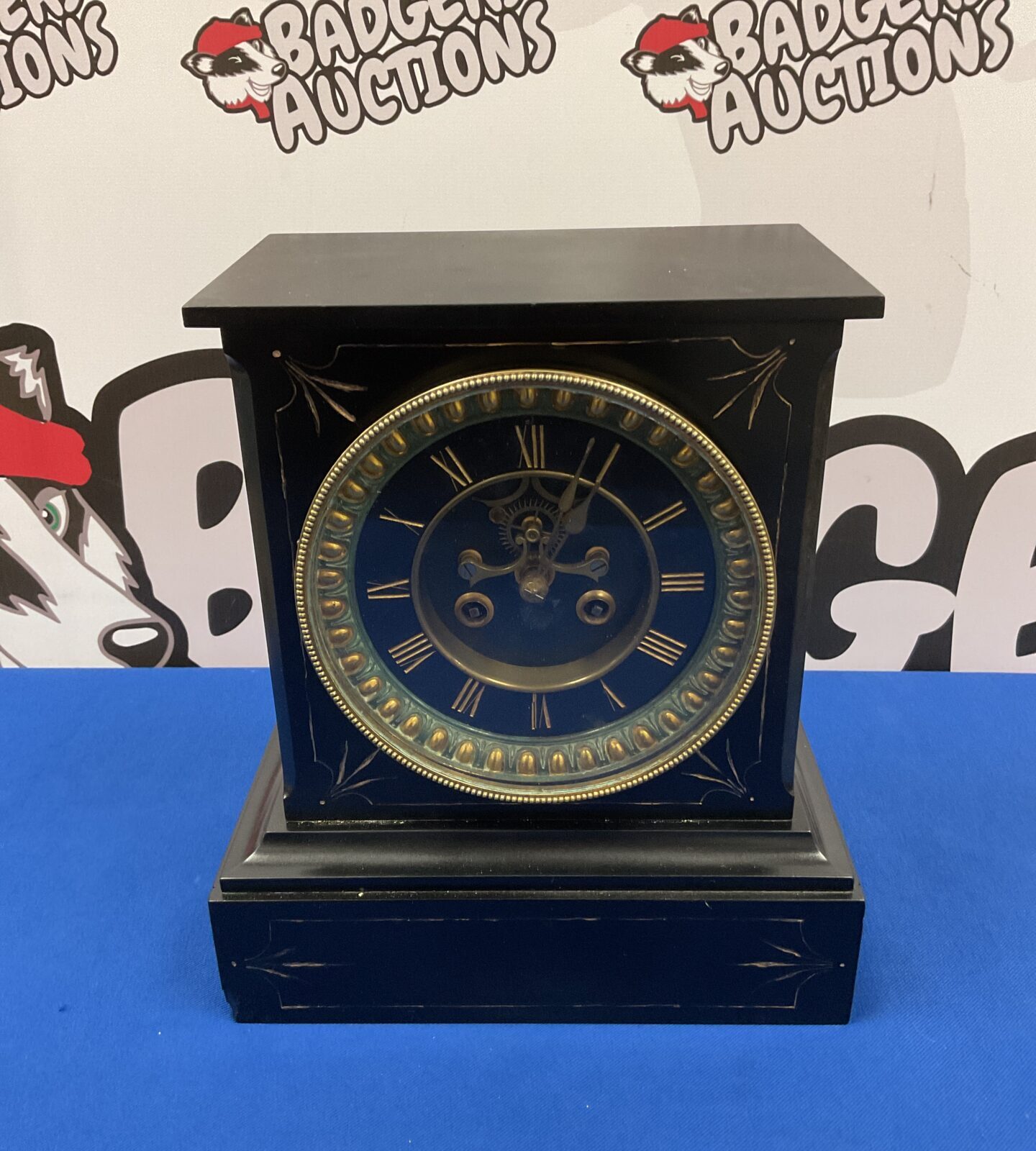 Front view of a Victorian slate mantle clock with brass face.
