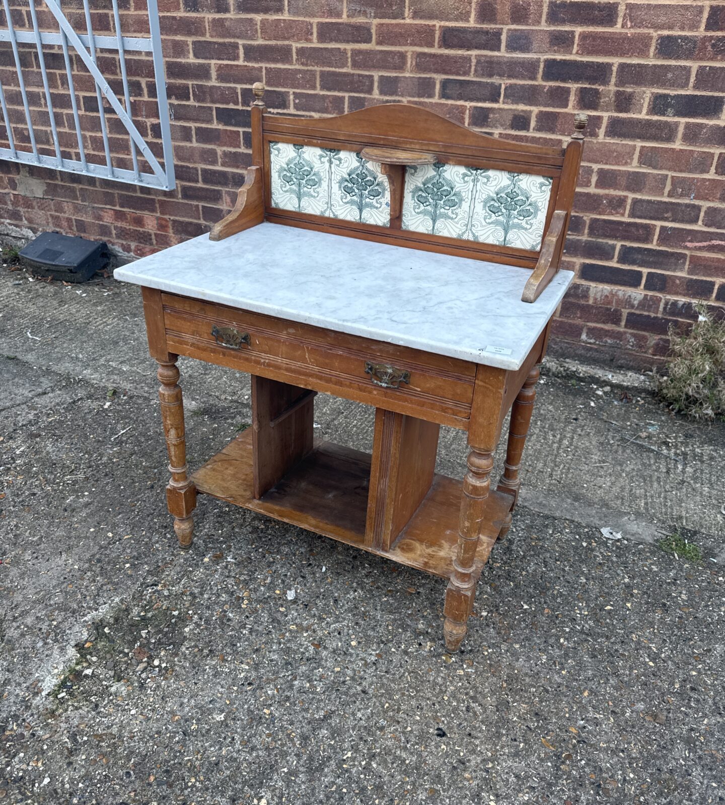 Victorian wash stand with marble top and decorative tile backsplash.