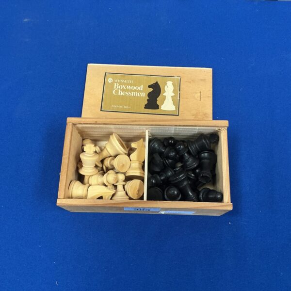 Vintage boxwood chessmen set on a dark surface.