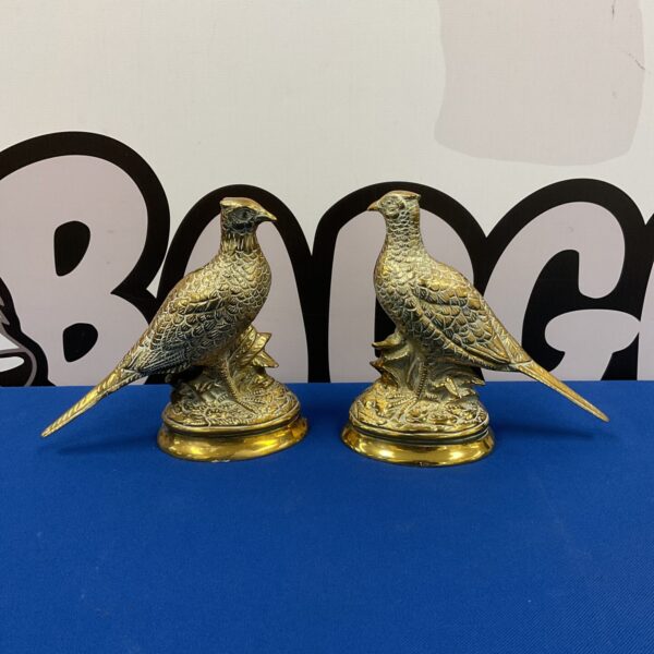 Pair of vintage brass pheasant statues on a dark surface.