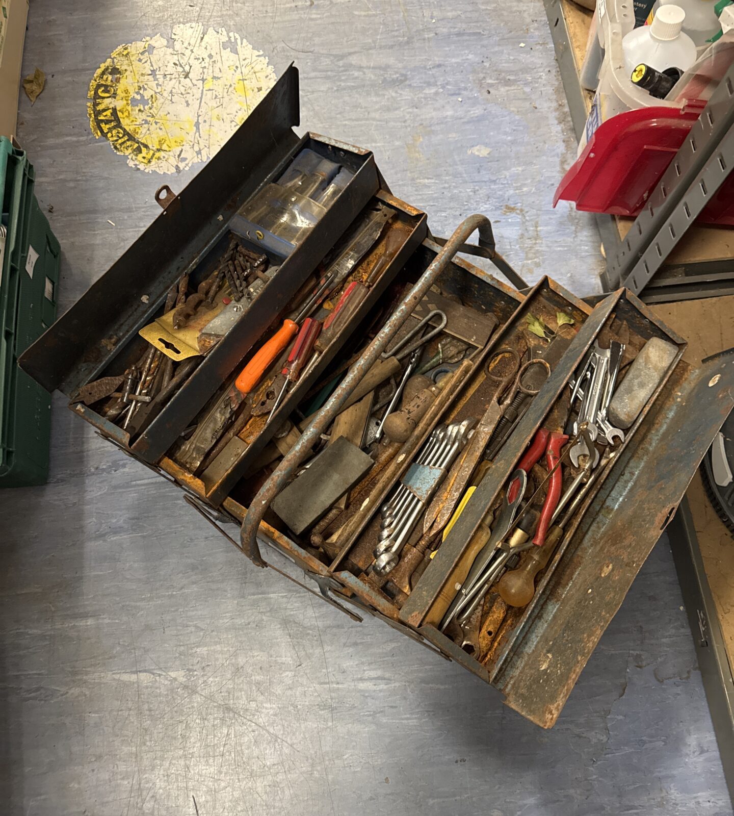 Vintage metal cantilever toolbox filled with antique tools.