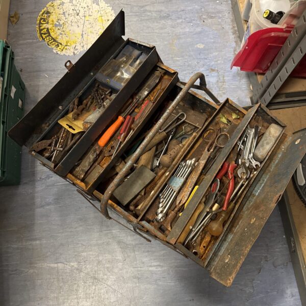 Vintage metal cantilever toolbox filled with antique tools.