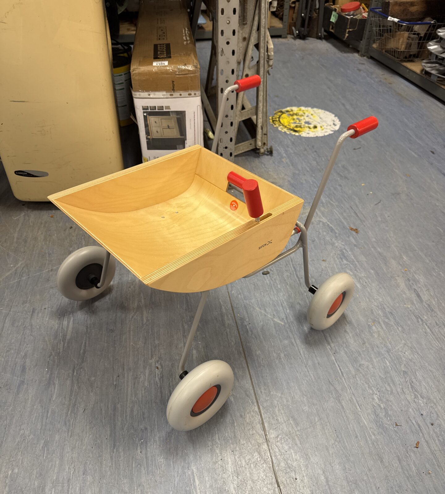 Vintage Sirch child’s wheelbarrow with red handles and grey wheels.