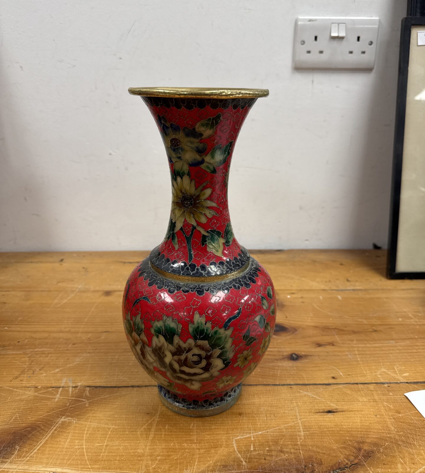 Vintage cloisonne vase with floral design and red background.