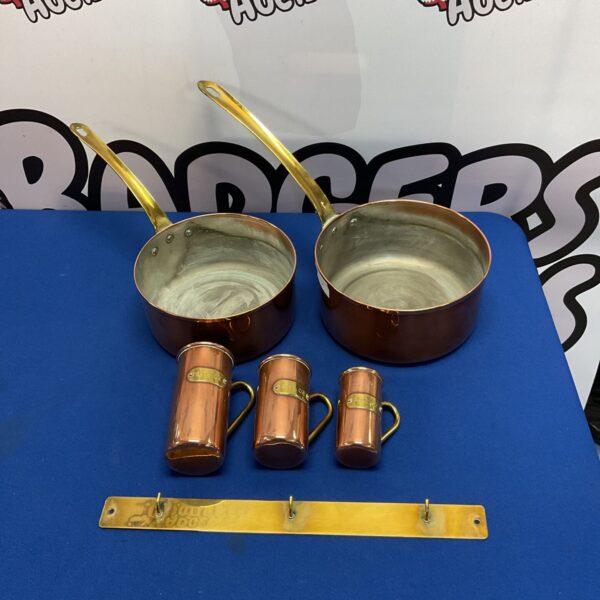 Vintage copper pans and measuring cups set for cooking.