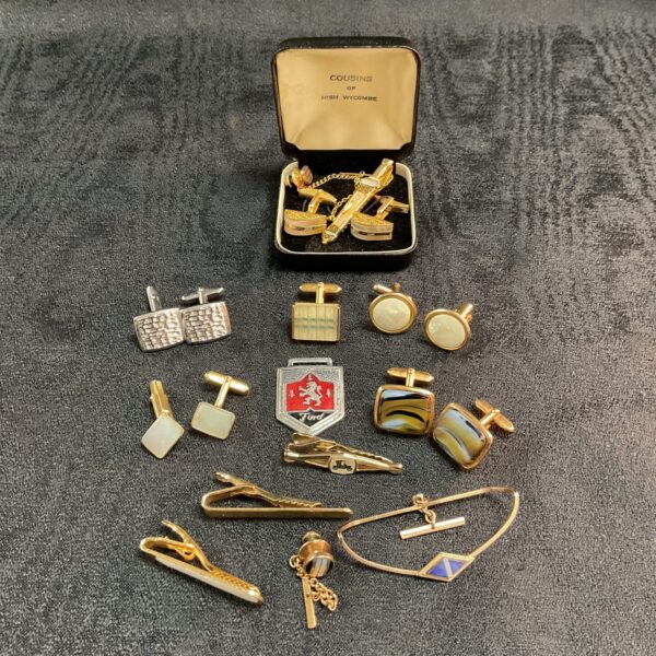 Vintage collection of gold-toned cufflinks and tie clips on display.