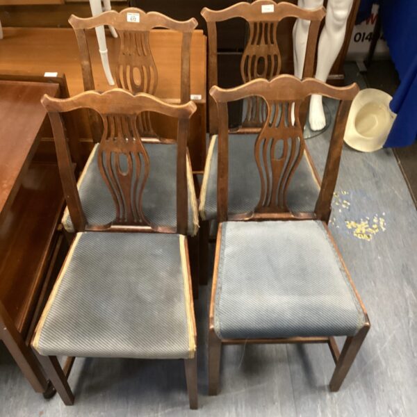 Set of four vintage wooden dining chairs with upholstered seats.